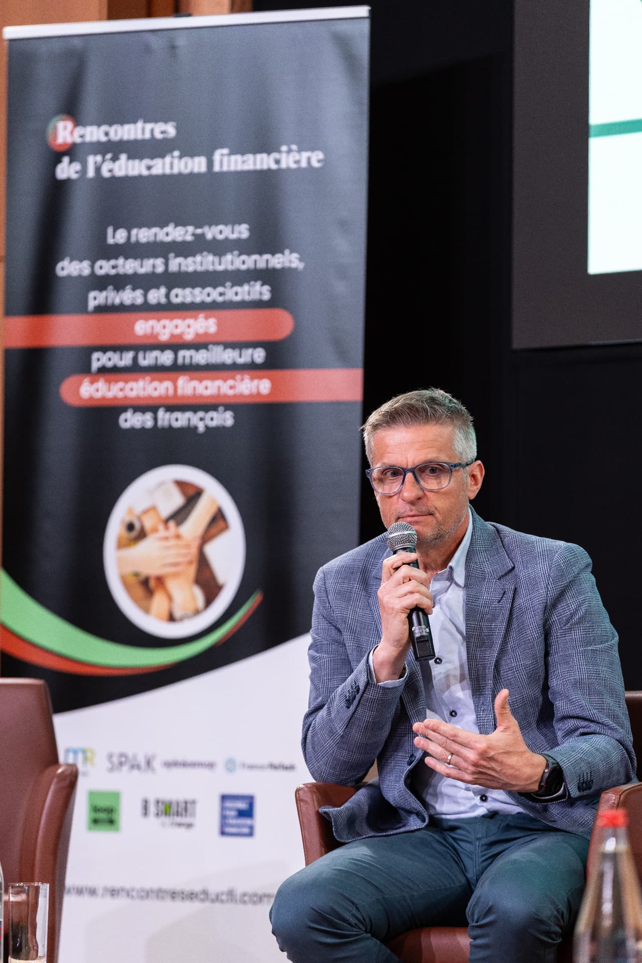Intervenant au micro devant le kakémono des Rencontres — Rencontres 2026